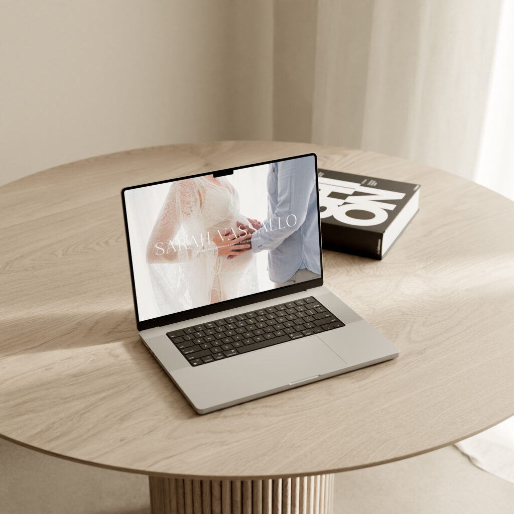Website sitting open on wooden table, with the screen showing a website home page for Sarah Vassallo Photography, Sydney newborn photographer