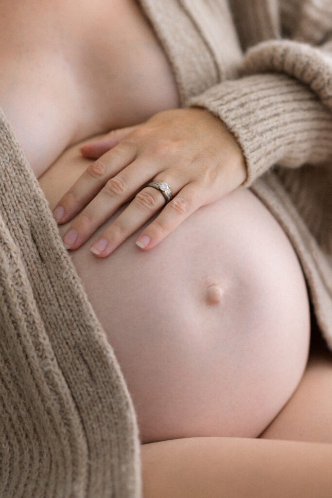 Close up of pregnant mother's hand gently resting on her belly photographed in Sarah Vassallo Photography studio