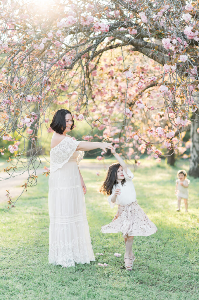 Mother twirling young daughter under cherry blossom tree during Sydney family photo session