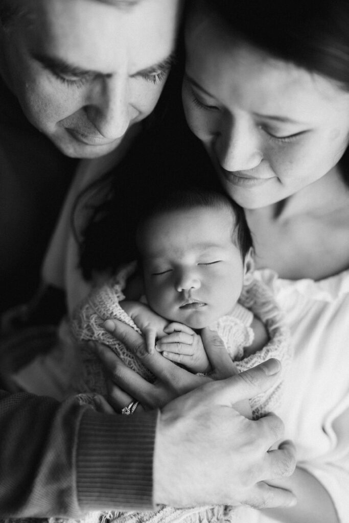 Modern Sydney Newborn Photography image of parents holding newborn baby in their arms sarah vassallo photography