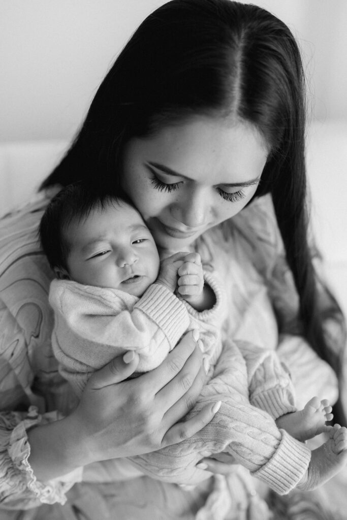 Newborn baby in mums arms in a curled-up pose by Sydney photographer Sarah Vassallo