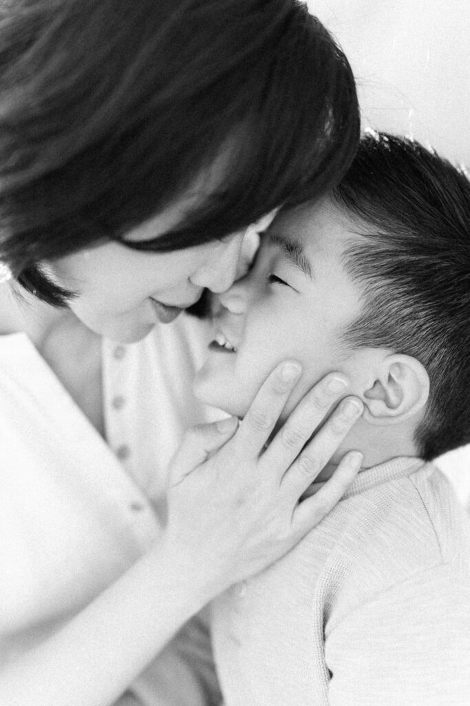 black and white image mother gently caressing young son's face and she holds him close