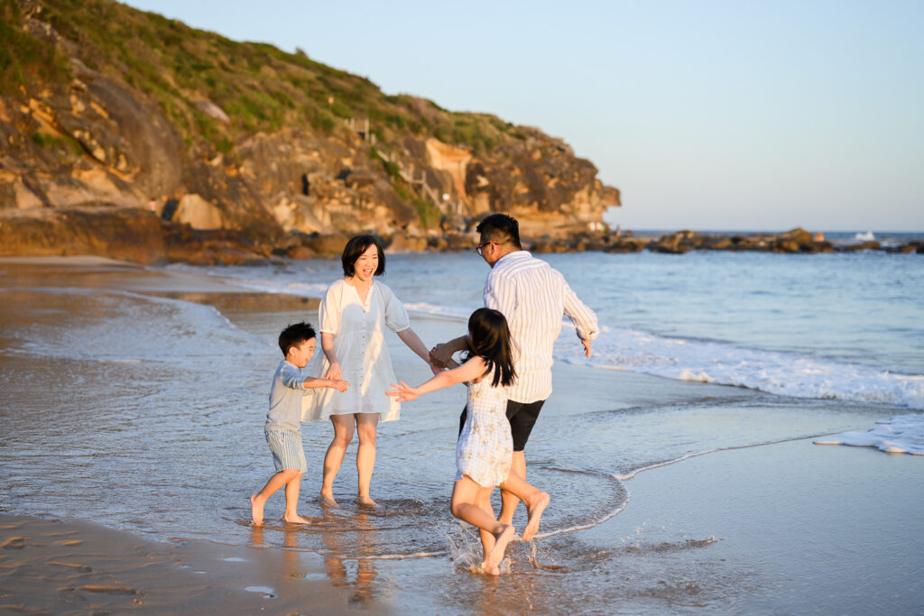 Family having fun playing together on the beach during family photo shoot in Sydney