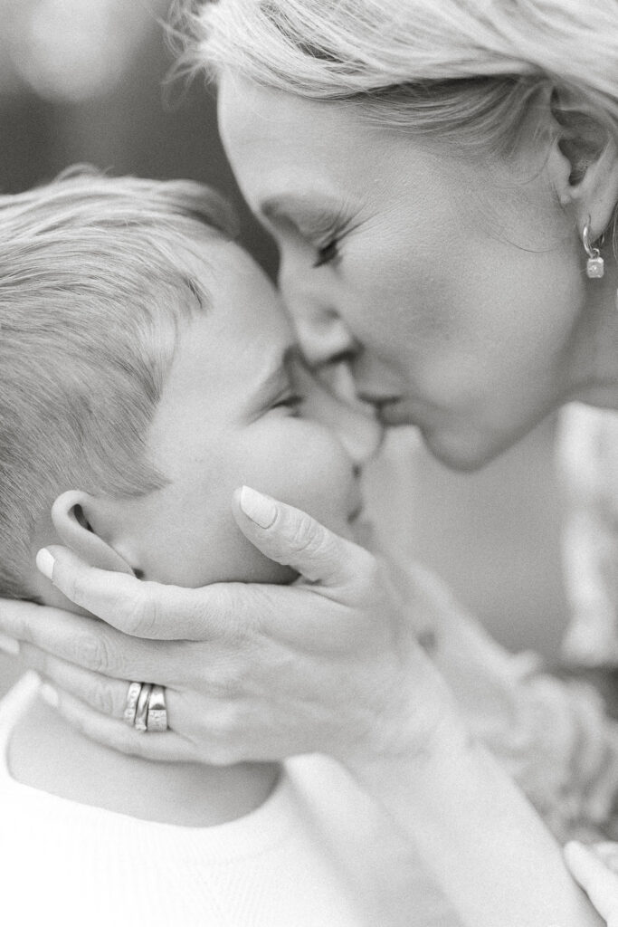 Black and white image of mother gently kissing son on the nose during family photoshoot in Eastern Suburbs Sydney
